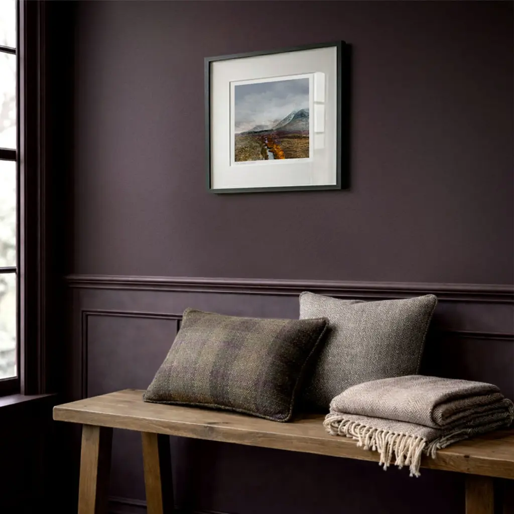 Glencoe Scottish Art print, framed on a wall in a hallway with Scottish decor - tweed cushions on an oak bench and aubergine coloured walls. Artwork by Carol McEwan www.carolmcewan.scot